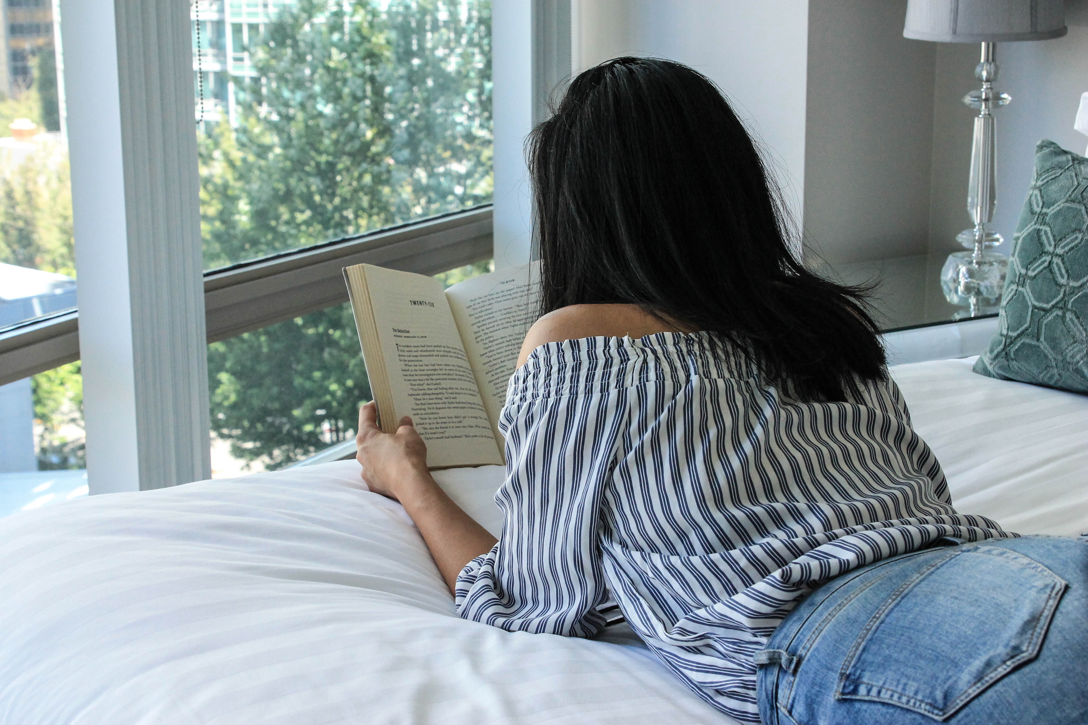 woman reading book on the bed