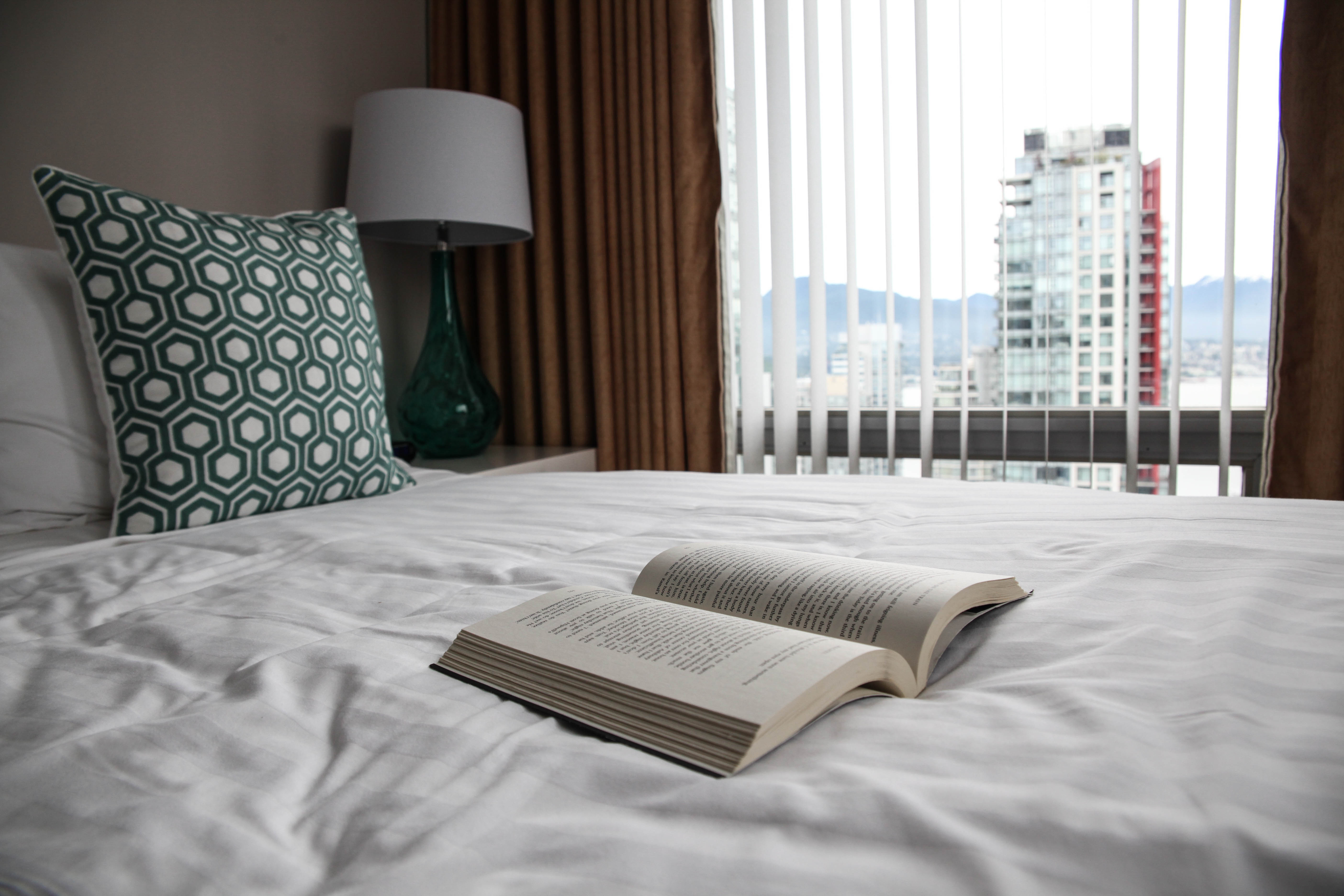 bed with green cushions and book at Vancouver Extended Stay